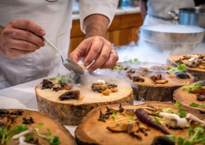 Cuisinier placant des champignons sur des assiettes en bois