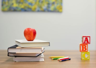Table avec des livres, une pomme, crayons et des blocs de lettre